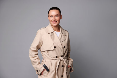 Young woman with hidden camera in her pocket on light gray backgroundの写真素材