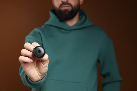 Man with hidden camera on brown background, closeup