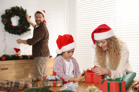 Happy family in Santa hats wrapping gifts and decorating room for Christmas, selective focusの写真素材