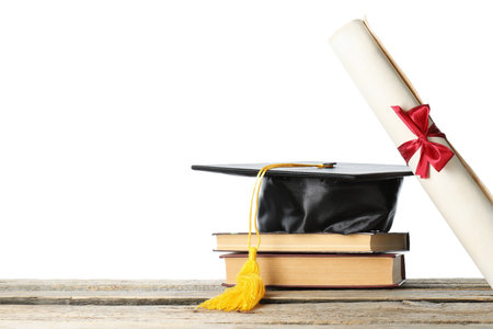 Diploma, books and graduation hat on wooden table against white backgroundの写真素材