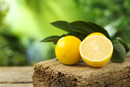 Fresh lemons with green leaves on wooden table outdoors, closeup. Space for textの写真素材