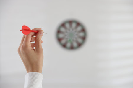 Woman with dart aiming at dartboard indoors, selective focusの写真素材