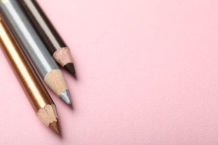 Color eye pencils on pink background, closeup. Space for textの写真素材