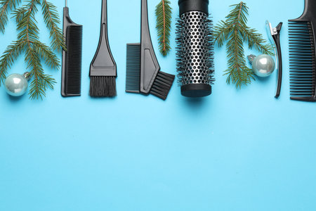 Hairdresser's tools, baubles and fir tree branches on light blue background, flat lay. Space for textの写真素材
