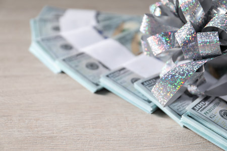 Dollar banknotes with bow on light wooden background, closeupの写真素材