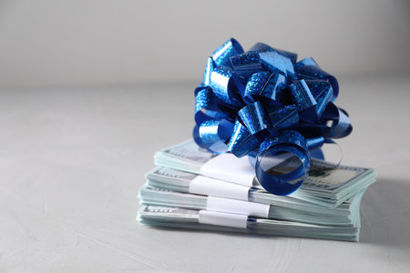 Dollar banknotes with bow on light background, closeup. Space for textの写真素材