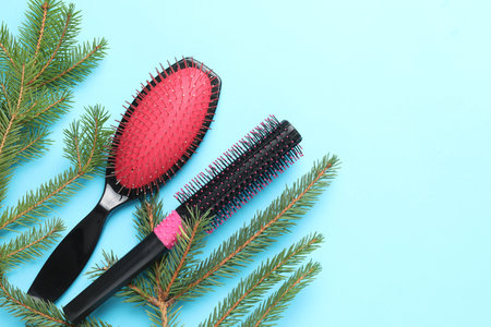 Hairdresser's tools and fir tree branches on light blue background, flat lay with space for text. Christmas greeting cardの写真素材