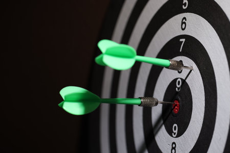 Dartboard with darts on black background, closeupの写真素材
