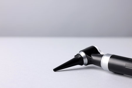 Hearing test. Modern otoscope on light gray background, closeup. Space for textの写真素材