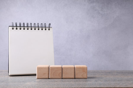 Blank cubes and notebook on wooden table. Mockup for designの写真素材