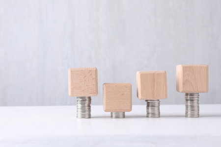 Blank wooden cubes and stacked coins on white table. Mockup for designの写真素材