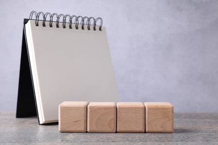 Blank cubes and notebook on wooden table. Mockup for designの写真素材
