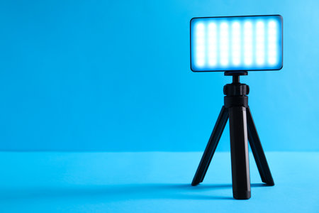 Stylish LED lamp on tripod against light blue background. Space for textの写真素材