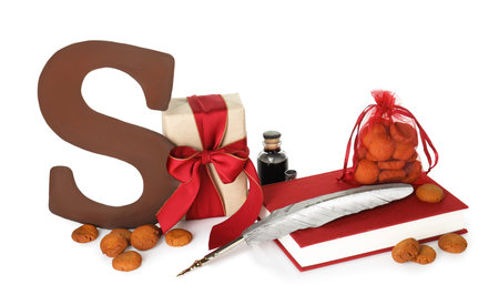 Saint Nicholas (Sinterklaas) day. Inkwell, feather, book, chocolate letter S, kruidnoten cookies and gift box isolated on whiteの写真素材