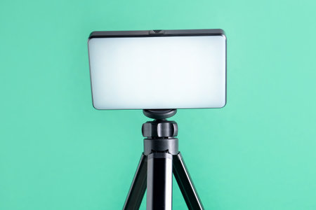 Stylish LED lamp on tripod against turquoise background, closeup