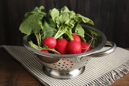 Fresh ripe radishes in colander on wooden tableの写真素材