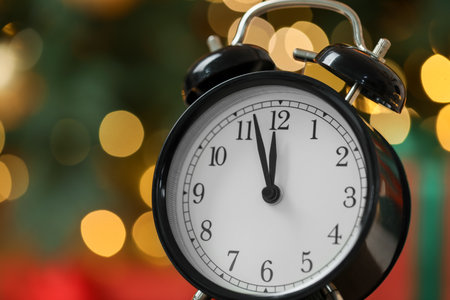 New Year greeting card. Alarm clock against color background with blurred lights, closeup with space...