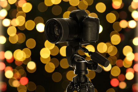 Professional camera against blurred lights on dark background, bokeh effectの写真素材
