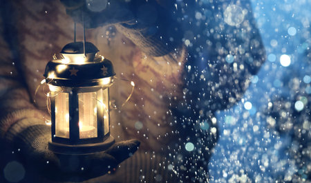 Merry Christmas. Woman holding lantern with string lights outdoors, closeup. Banner design