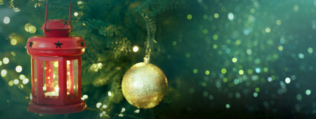 Christmas ball and lantern hanging from fir tree branches, banner design. Holiday card with bokeh...