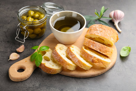 Slices of ciabatta, spices and olives on gray table, closeupの写真素材