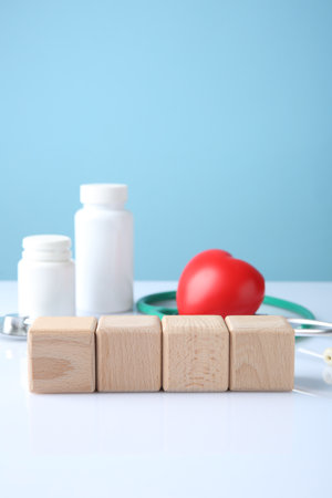Stethoscope, pills, heart figure and blank wooden cubes on white table against light blue background. Mockup for designの写真素材