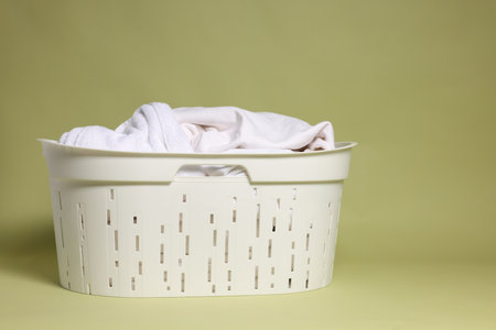Plastic basket full of laundry against backgroundの写真素材