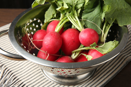 Fresh ripe radishes in colander on table, closeupの写真素材