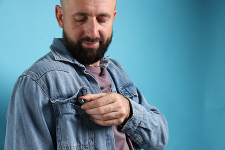 Man with hidden camera in his pocket on light blue background, space for textの写真素材