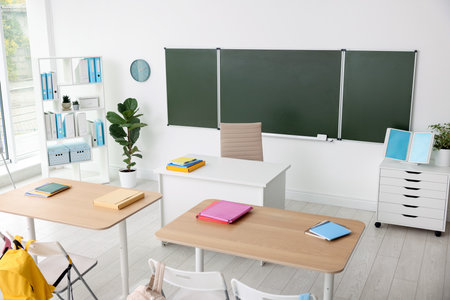 Green chalkboard and stylish furniture in classroom. Mockup for designの写真素材