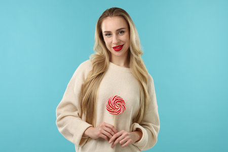 Woman with lollipop on light blue backgroundの写真素材