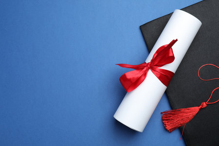 Diploma and graduation hat on blue background, top view. Space for textの写真素材