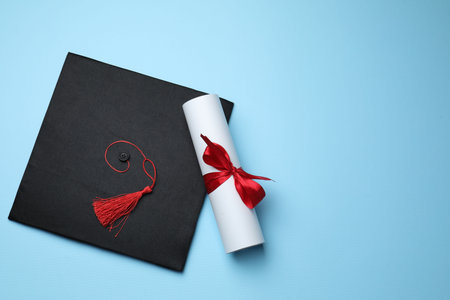 Diploma and graduation hat on light blue background, top view. Space for textの写真素材