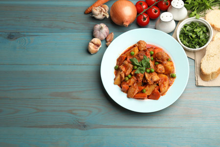 Delicious cooked stew and ingredients on light blue wooden table, flat lay. Space for textの写真素材