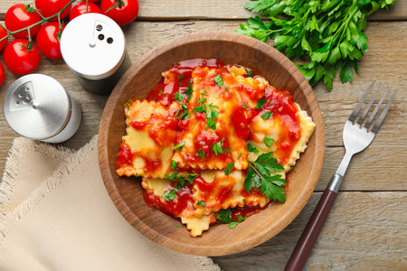 Delicious ravioli with tomato sauce and parsley served on wooden table, flat layの写真素材