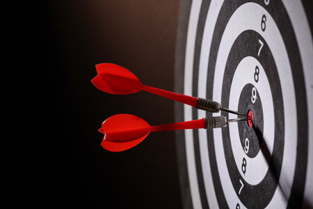 Dartboard with darts on black background, closeupの写真素材