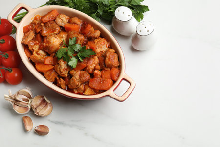 Delicious cooked stew in baking dish and fresh ingredients on white marble table, flat lay. Space for textの写真素材