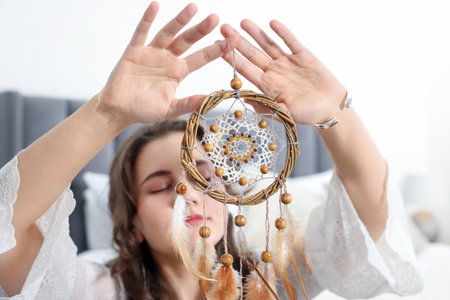 Woman with beautiful dream catcher in bedroom, selective focusの写真素材