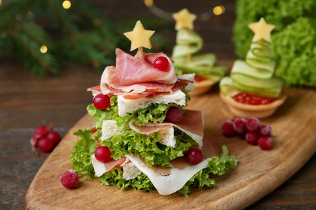 Christmas tree shaped snack made with lettuce, ham, croutons and berries on wooden table, closeupの写真素材