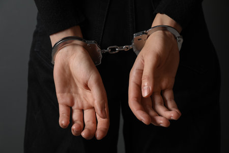 Woman in metal handcuffs on gray background, closeupの写真素材