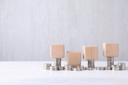 Blank wooden cubes and stacked coins on white table. Mockup for designの写真素材