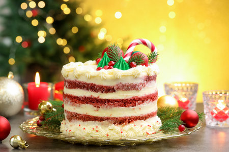 Tasty cake with Christmas decor on gray table against blurred lightsの写真素材