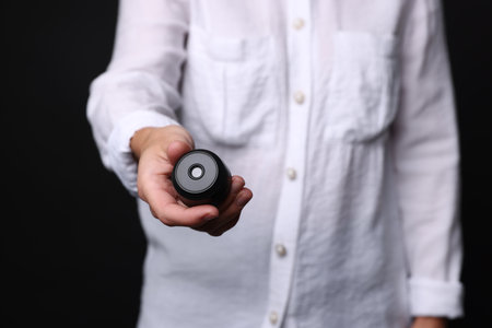 Young woman with hidden camera on black background, closeupの写真素材