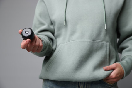 Young woman with hidden spy camera on light gray background, closeupの写真素材