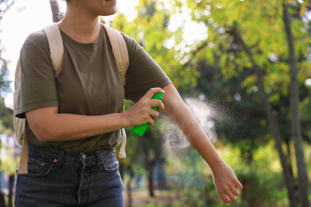 Woman spraying tick repellent onto arm in park, closeup. Space for textの写真素材