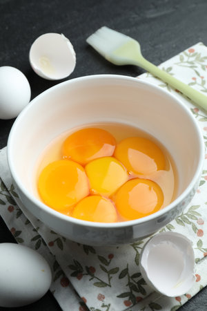 Raw eggs, yolks and brush on black table, closeupの写真素材