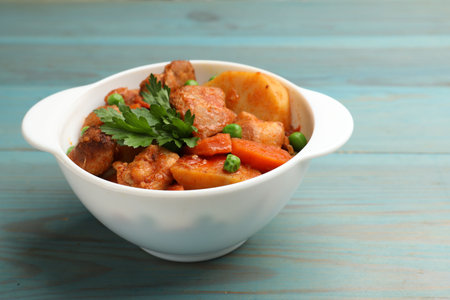 Delicious cooked stew in bowl on light blue wooden table, closeupの写真素材
