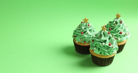 Christmas tree shaped cupcakes on green background, closeup. Space for textの写真素材