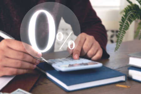 Man with using calculator at table, closeup. 0 percent representing zero commissionの写真素材