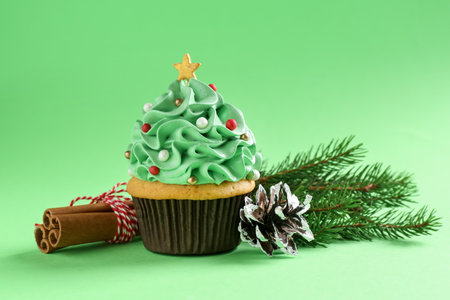 Christmas tree shaped cupcake, cinnamon and festive decor on green background, closeupの写真素材